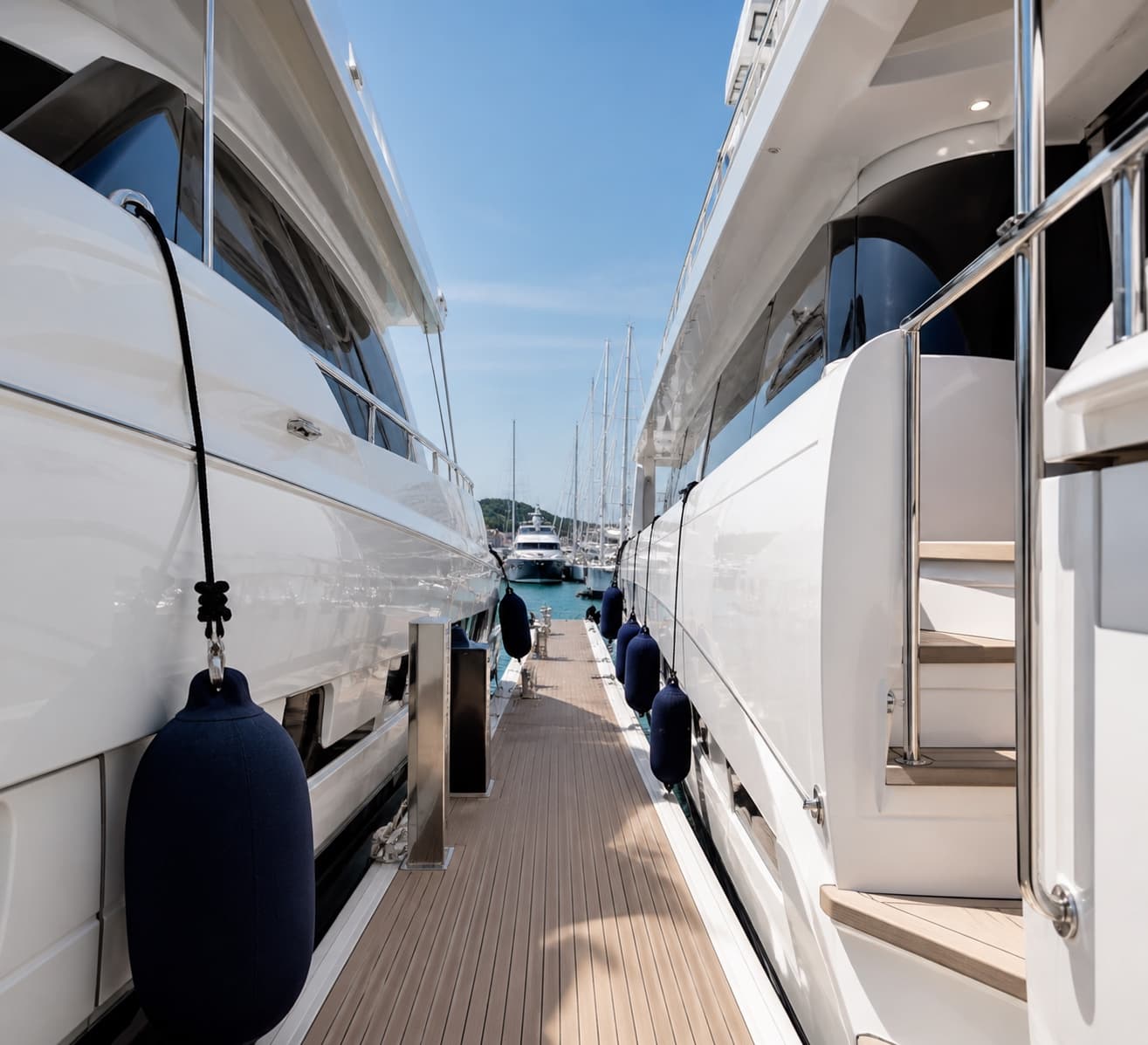 Walkway between two white yachts in a marina
